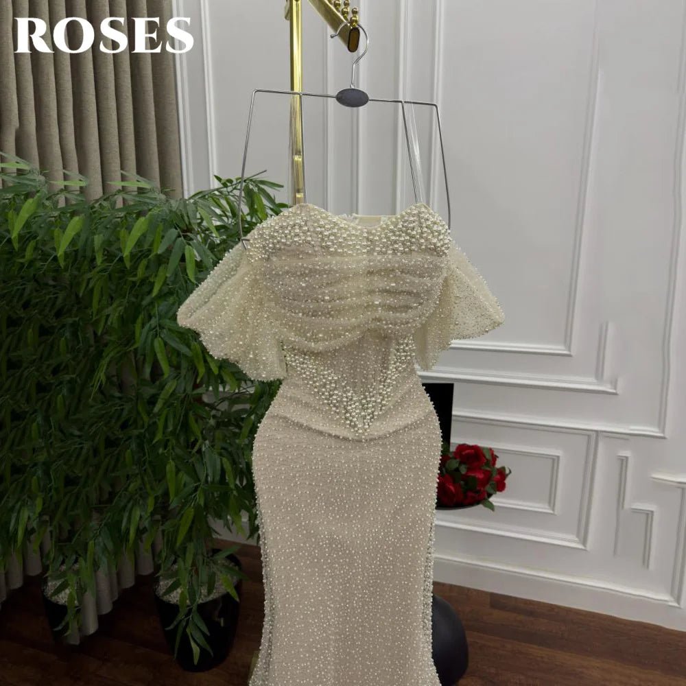 Beaded evening gown on a mannequin against a decorative wall with plants.