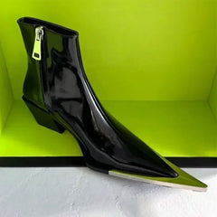 Black high-heeled shoe with a pointed toe on a green background