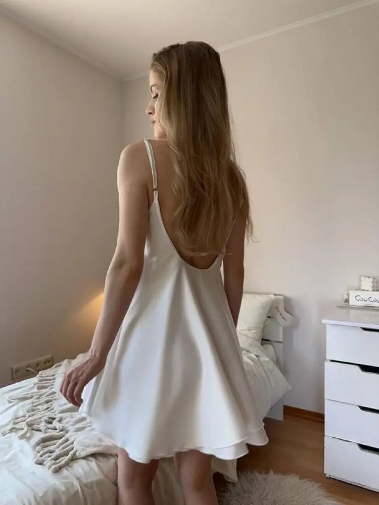 Woman in a white dress standing in a bedroom