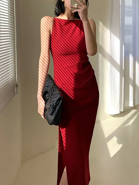 Person wearing a red dress holding a black clutch in a room with sunlight streaming in.