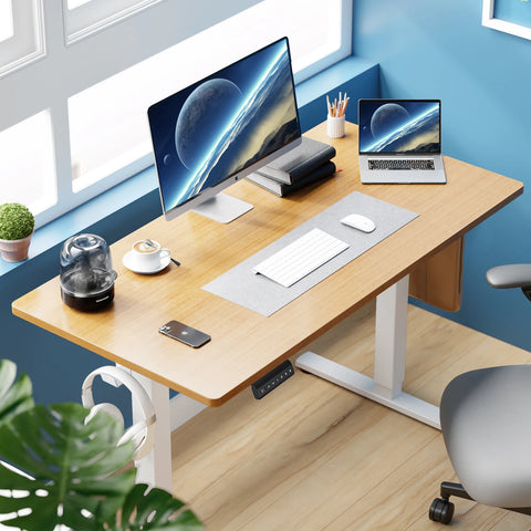 Modern office desk with computer setup, chair, and plants in a bright room.