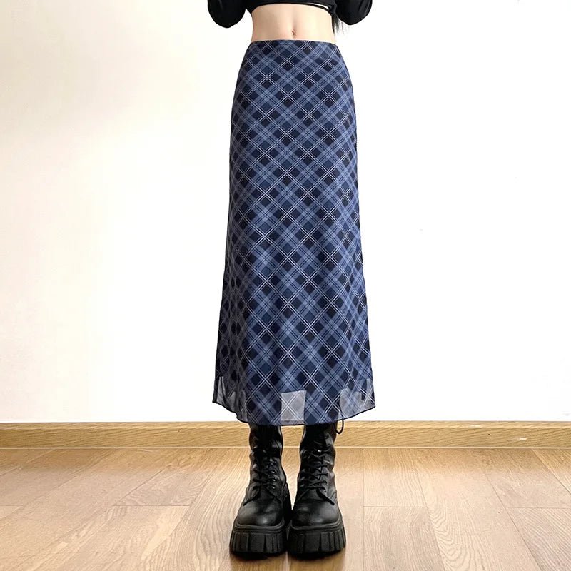 Person wearing a blue plaid skirt with black boots on a wooden floor.