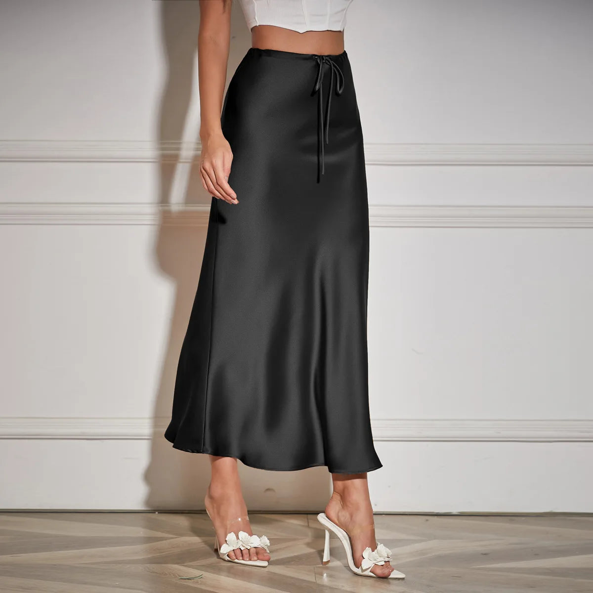 Black satin skirt worn by a person on a neutral background
