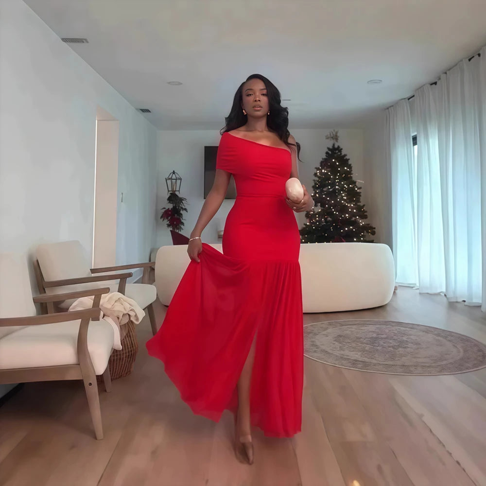 Woman in a red dress standing in a modern living room with a Christmas tree.
