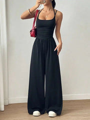 Person wearing a black jumpsuit with a plain background