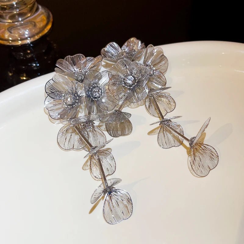 Silver floral earrings on a white surface with a dark background