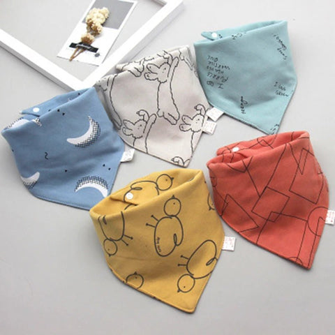 Five colorful baby bibs with different patterns on a light gray surface.
