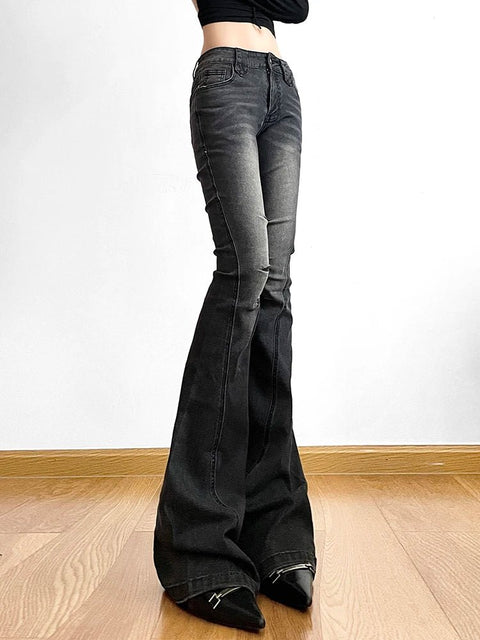 Person wearing black flared jeans on a plain background