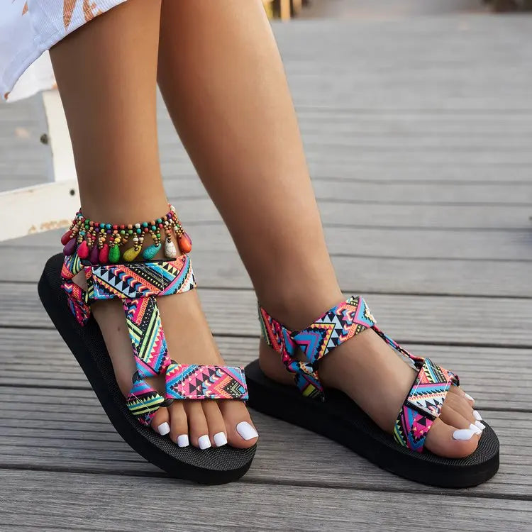 Colorful tribal sandals on feet standing on a wooden floor