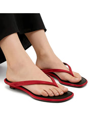 Red and black sandals worn by a person on a white background