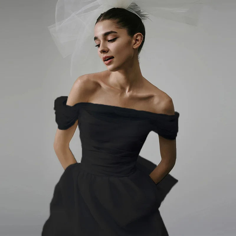 Woman wearing a black off-shoulder dress against a plain background