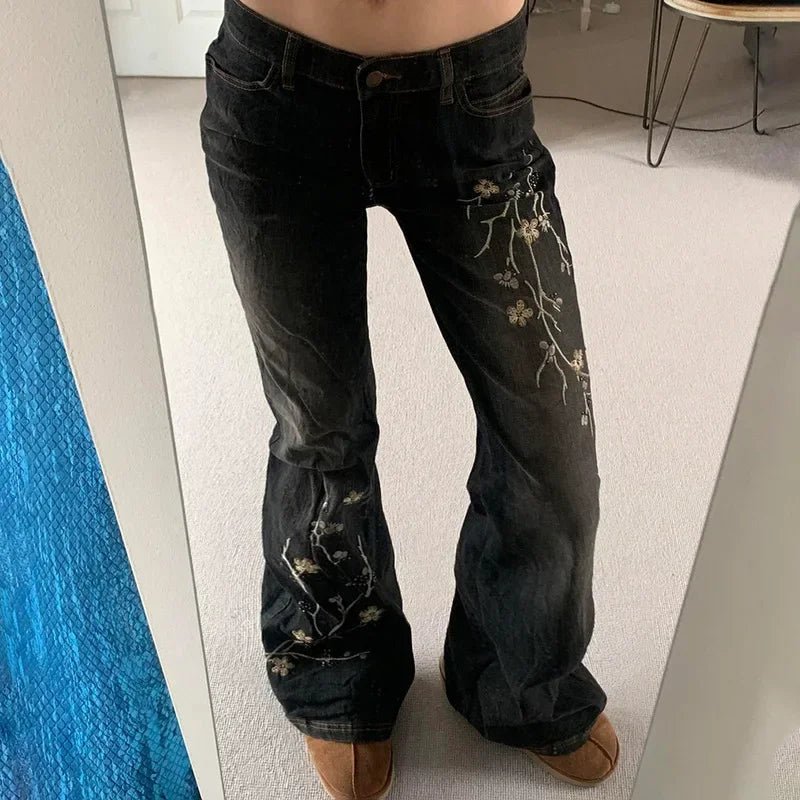 Black jeans with floral embroidery worn by a person indoors.