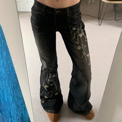 Black jeans with floral embroidery worn by a person indoors.