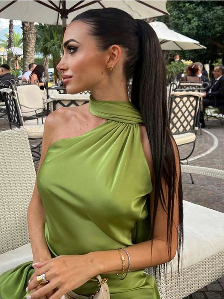Woman in a green dress sitting outdoors with a blurred background