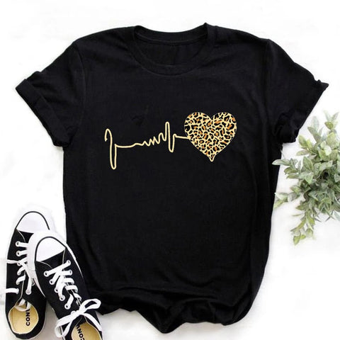 Black t-shirt with gold heart and line design, paired with white sneakers on a light background
