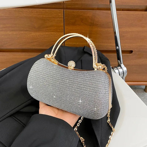 Silver glittery handbag with gold accents held by a person against a wooden background