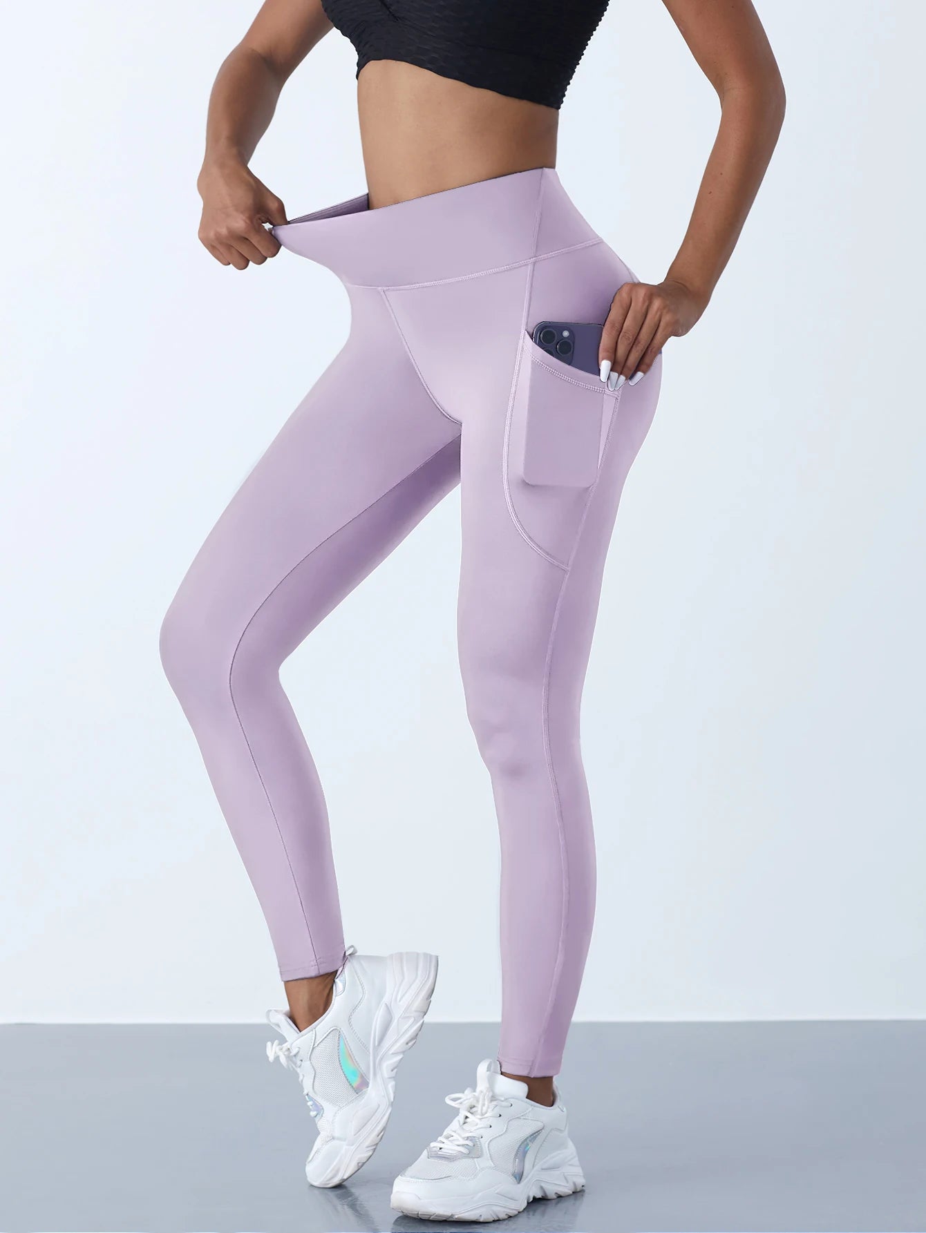 Person wearing lavender leggings with a pocket on a light gray background