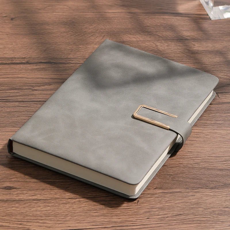 Gray notebook with a gold buckle on a wooden surface