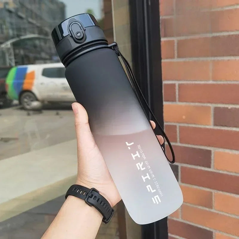 Person holding a gradient water bottle with 'SPIRIT' branding outdoors.