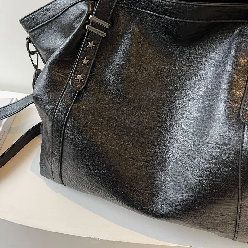 Black leather handbag with star-shaped studs on a white background