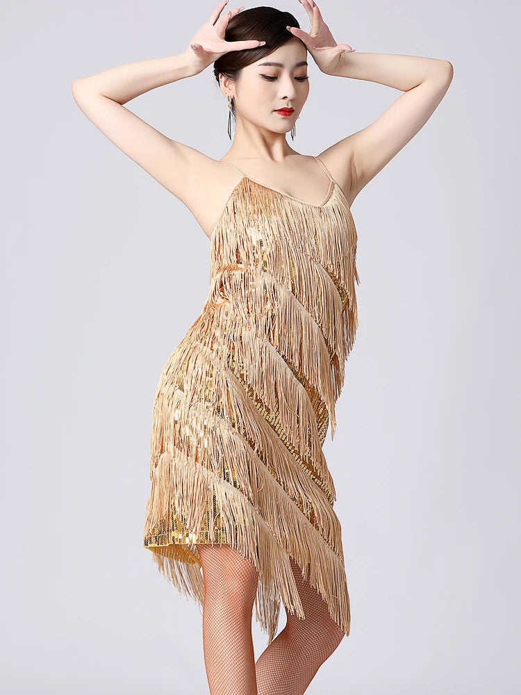 Woman wearing a gold fringe dress against a gray background