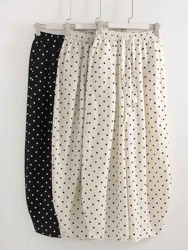 Two pairs of polka dot pants hanging on a rack against a white background.