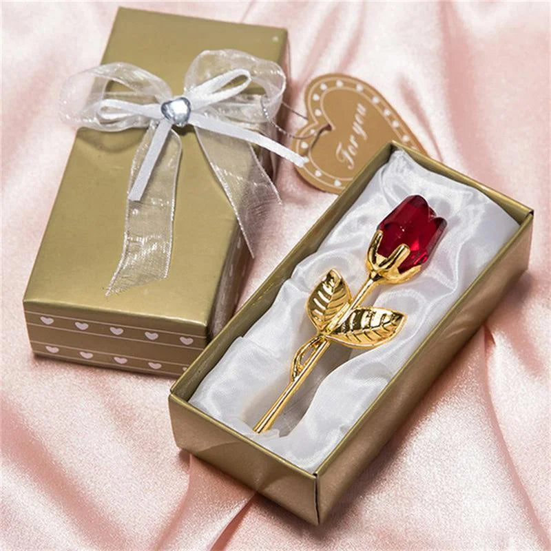Gold rose with red gemstone in a decorative box on a pink fabric background