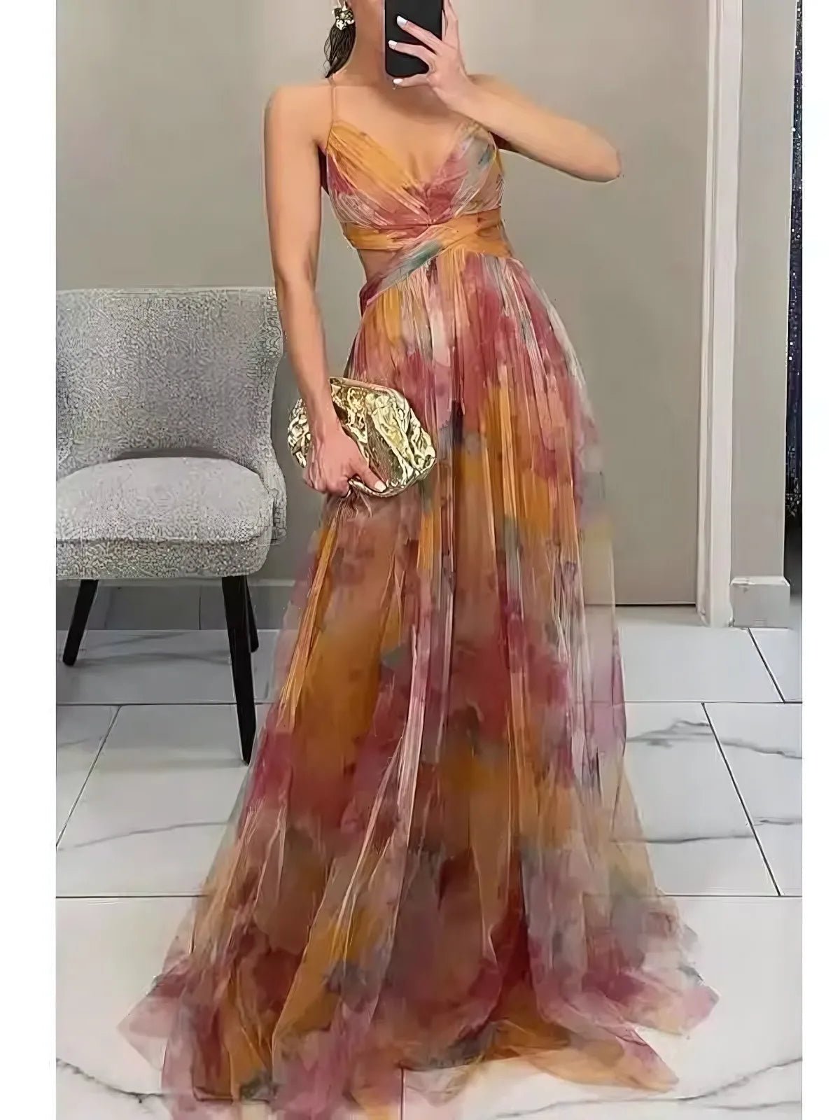 Woman wearing a colorful floral dress holding a gold clutch in an indoor setting.