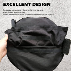Black bag with a hand holding it, showing the closure points on an gray background.
