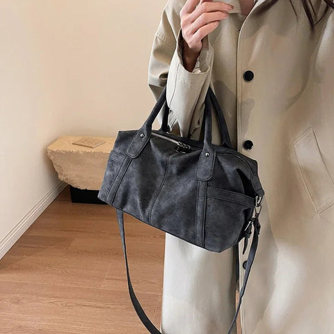 Person holding a black handbag in a neutral setting