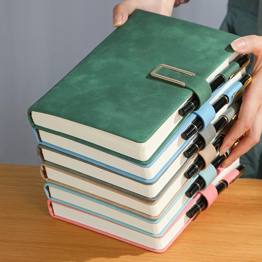 Stack of colorful notebooks with a pen on a wooden surface