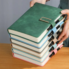 Stack of colorful notebooks with a pen on a wooden surface