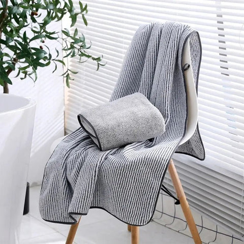 Gray textured blanket draped over a chair with a plant in the background