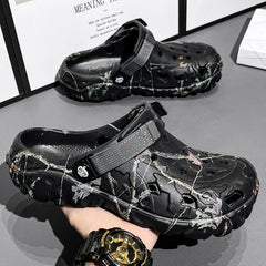 Black clogs with camouflage pattern worn by a person on a gray surface.
