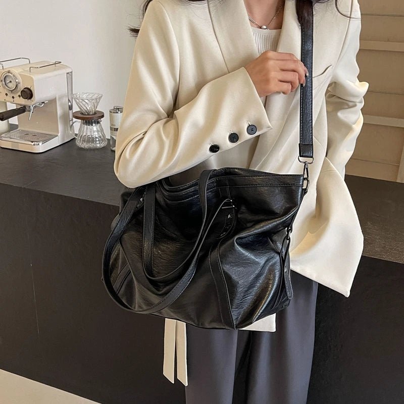 Person holding a black leather bag in an indoor setting