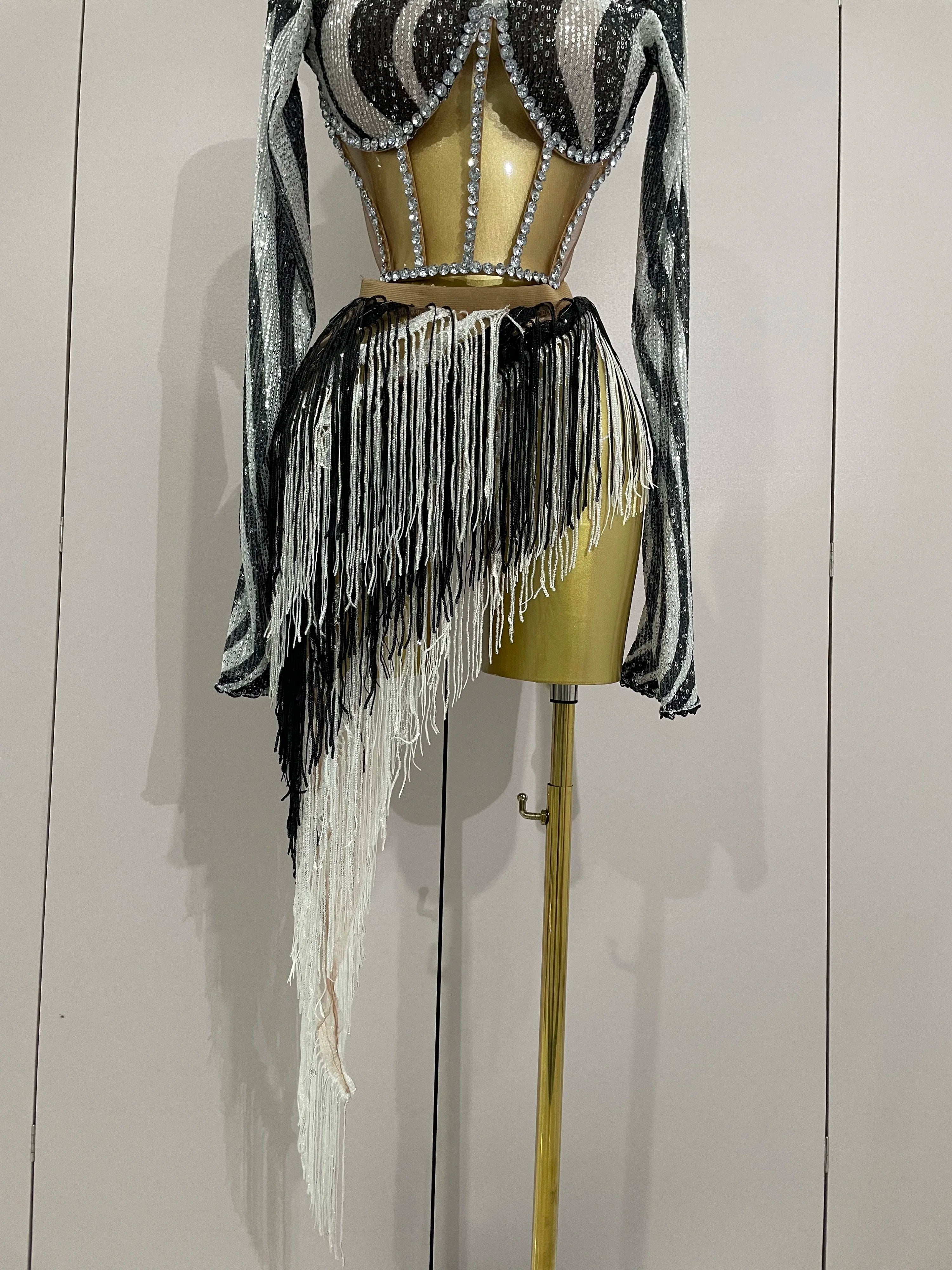 Black and white fringe outfit on a mannequin against a plain background