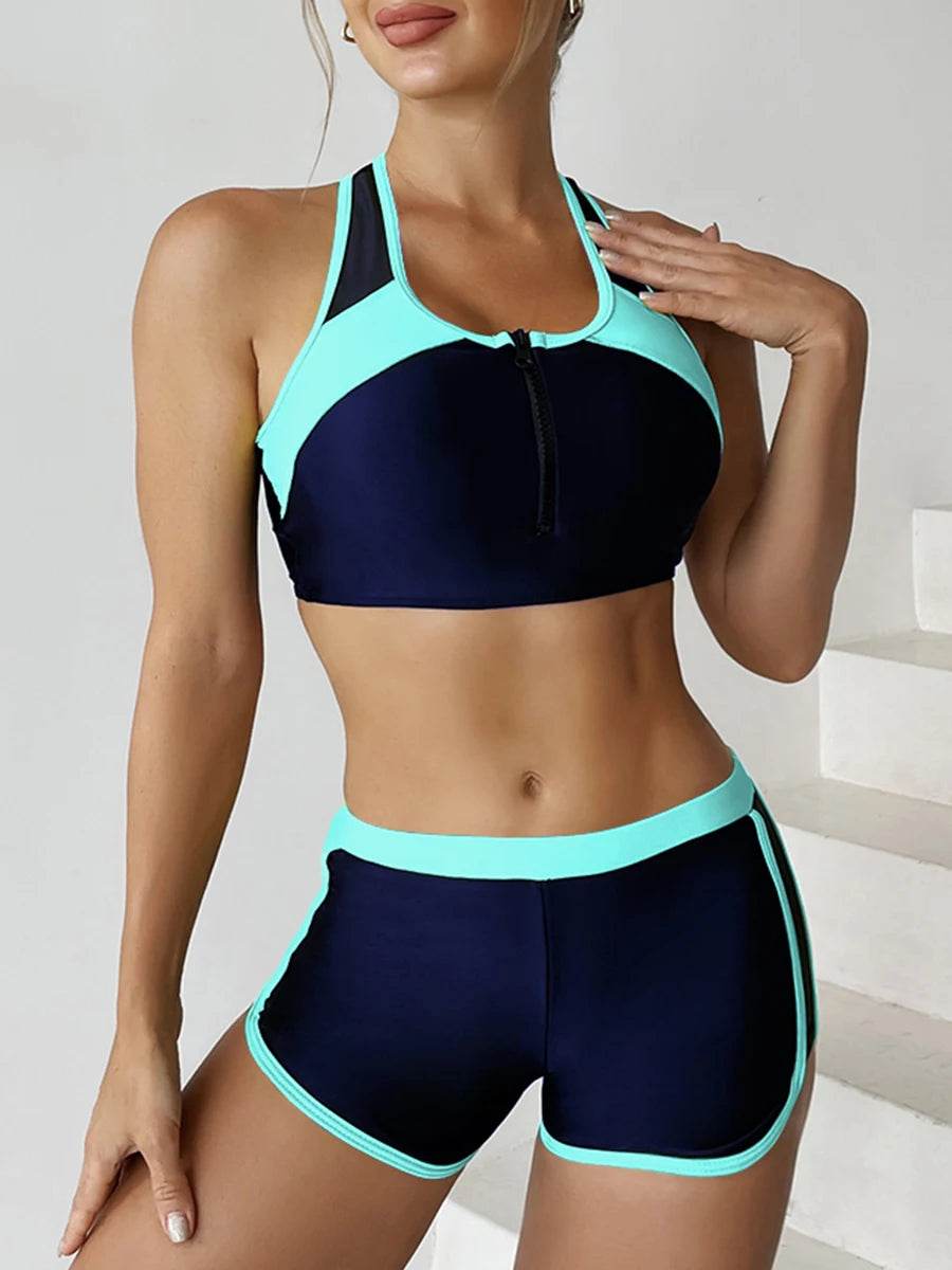 Woman wearing a black and teal sports bra and shorts set on a neutral background