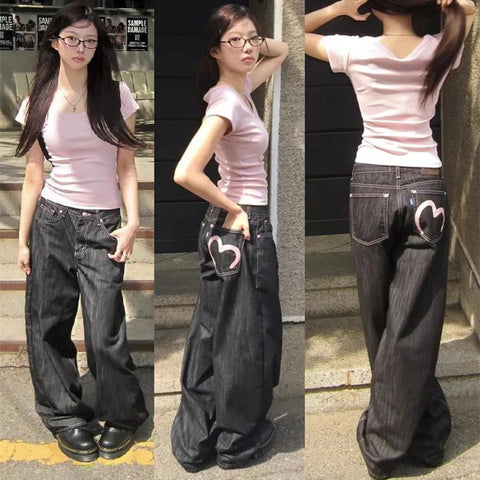 Woman wearing a pink shirt and black wide-leg jeans with heart designs, posing on steps.