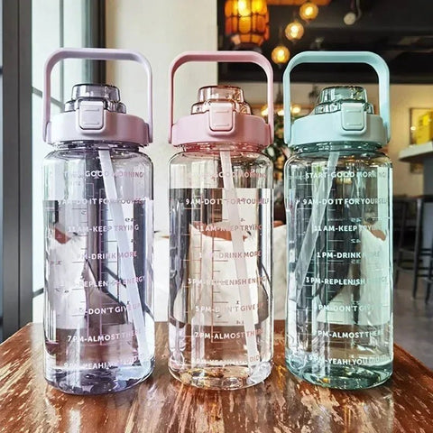 Three transparent water bottles with colorful lids on a wooden surface.