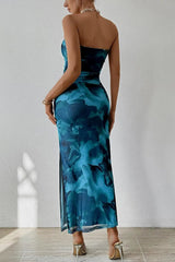 Woman wearing a strapless blue floral dress against a white wall.