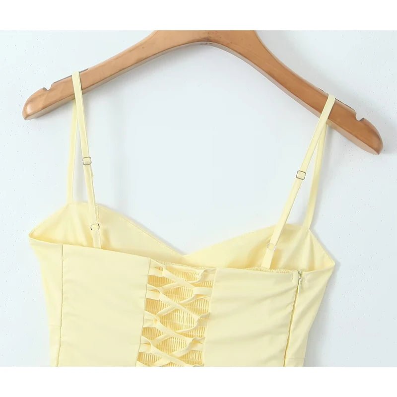 Yellow crop top with lace detail on a wooden hanger against a white background