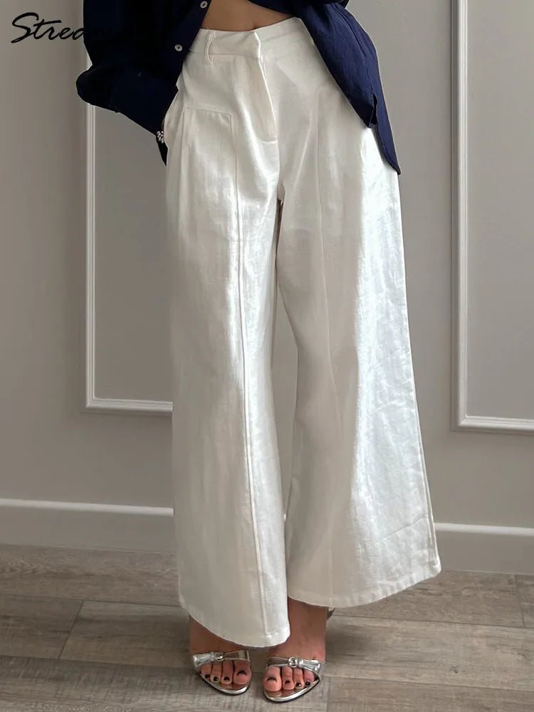 Person wearing white wide-leg pants with a navy jacket in a minimal indoor setting