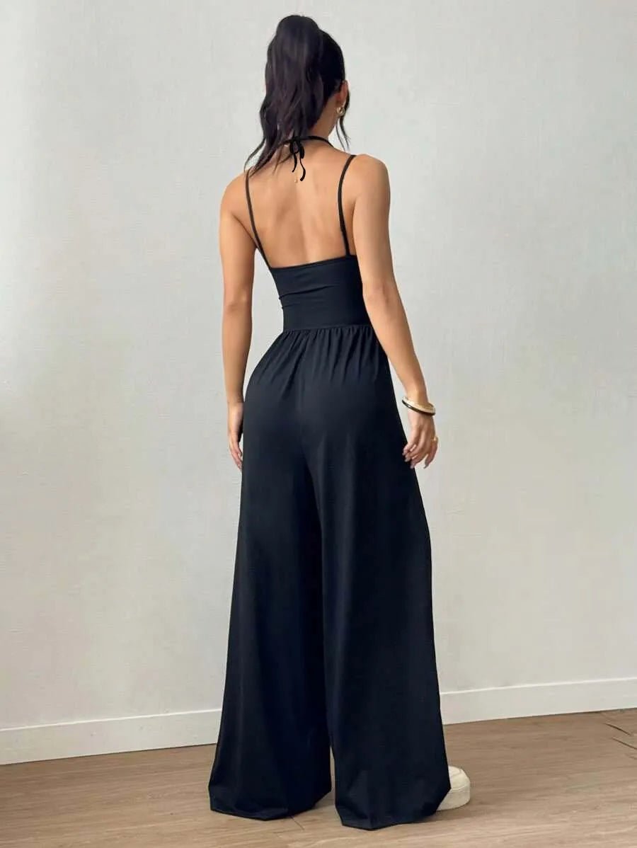 Woman wearing a black jumpsuit against a plain background