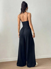 Woman wearing a black jumpsuit against a plain background
