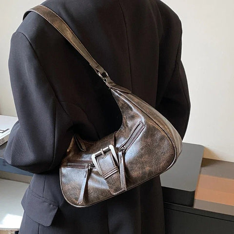 Person wearing a dark coat with a brown leather shoulder bag.