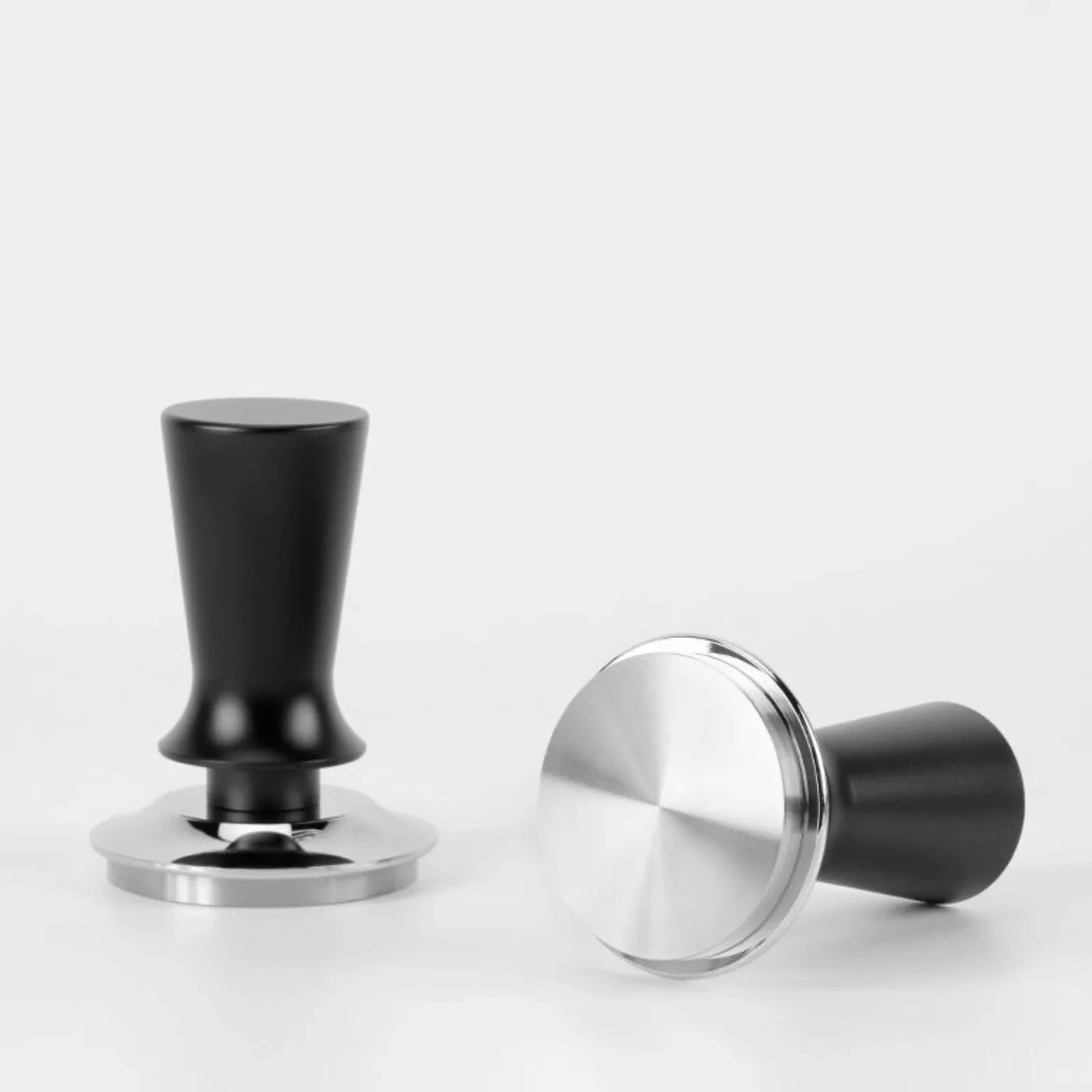 Two coffee tampers, one black and one silver, on a white background