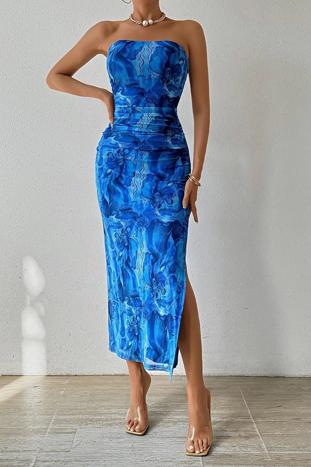 Woman wearing a blue strapless dress with a slit on a plain background