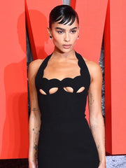 Person wearing a black dress with cut-out design against a red background
