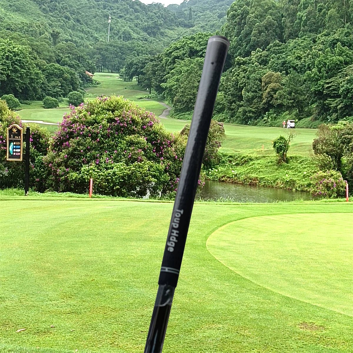 Golf club shaft with 'Four Horse' branding on a golf course with greenery and water in the background