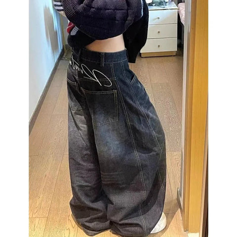 Person wearing wide-leg jeans in a room with wooden flooring.